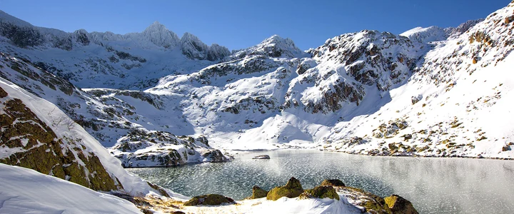 Lago y laderas rocosas cubiertos de nieve